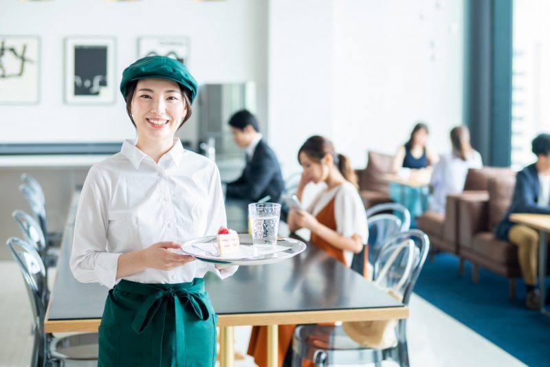 お店の中でケーキと飲み物を運ぼうとしている店員1名