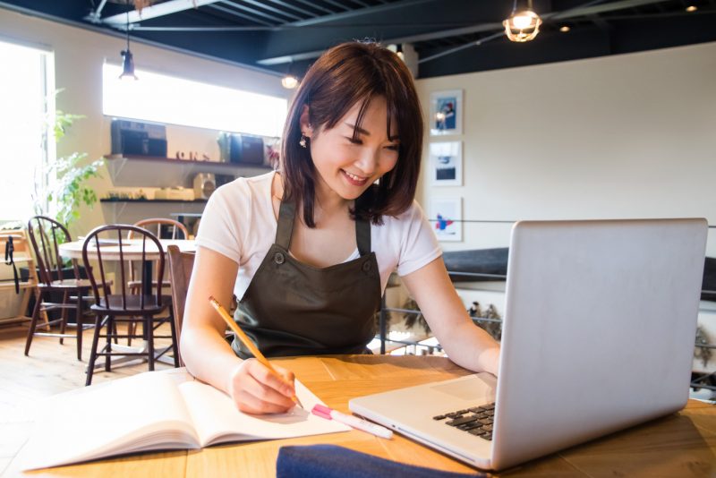 女性がPCとノートを見ている写真