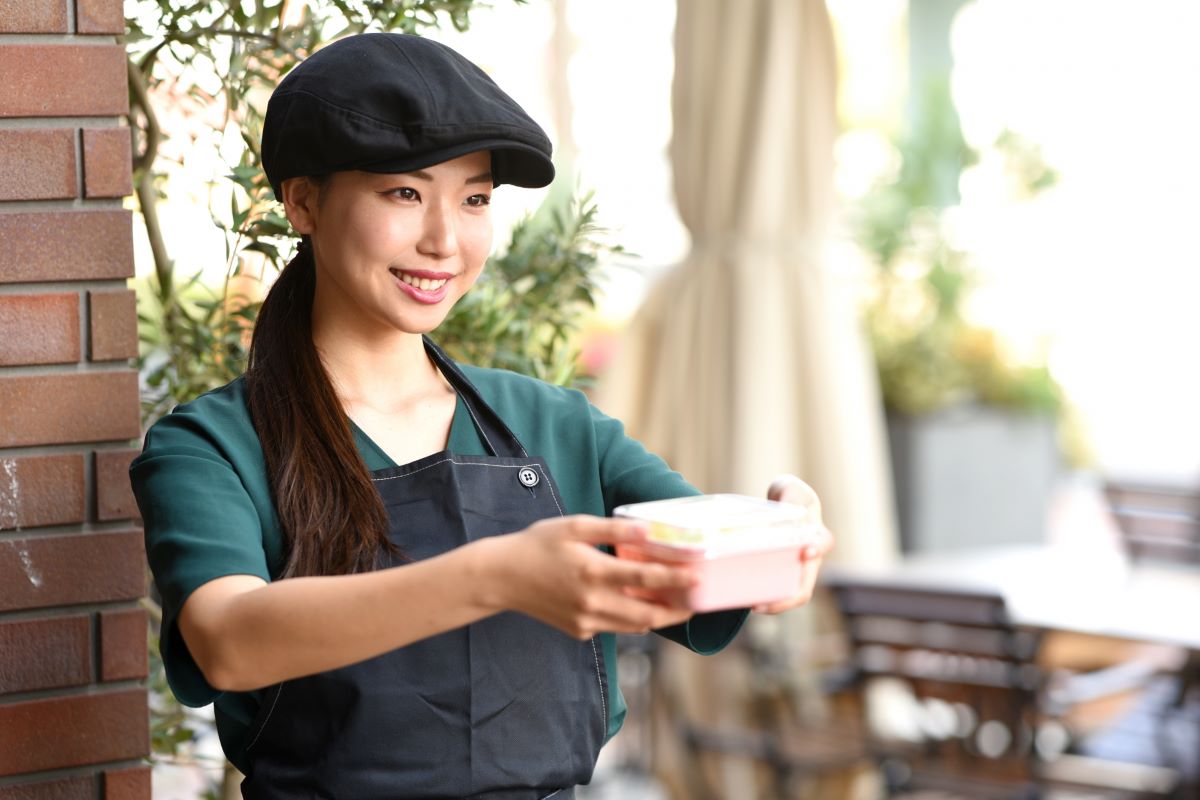 カフェ店員の女性がお弁当箱を持っている写真