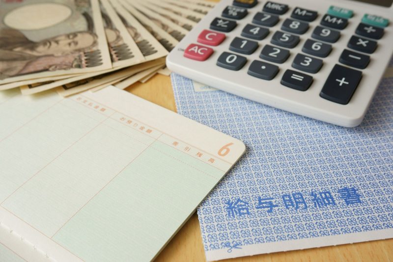 給料明細と電卓と預金通帳と一万円札